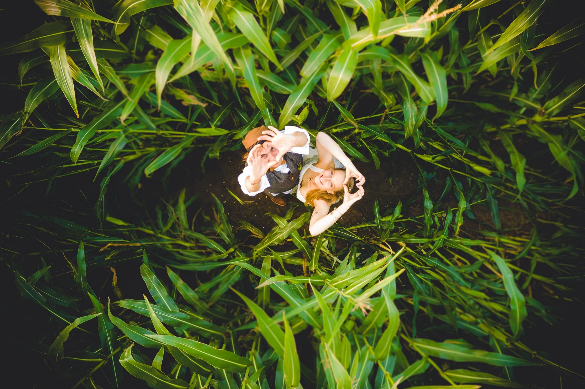 Wedding couple forming heart shapes with their hands in a garden